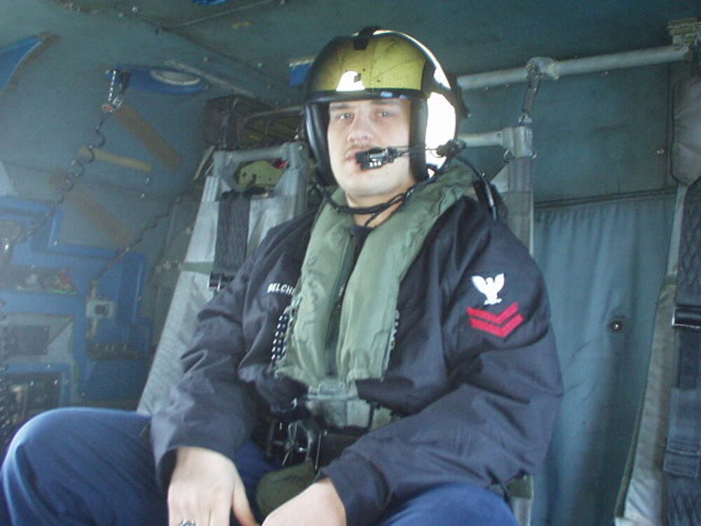Adam Belcher in flight gear aboard a Navy helicopter